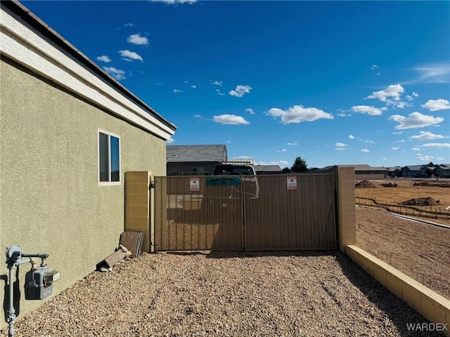 view of property exterior featuring fence, a gate, and stucco siding