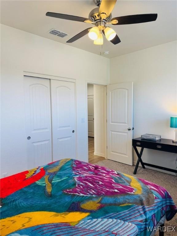 carpeted bedroom featuring a ceiling fan, a closet, and visible vents