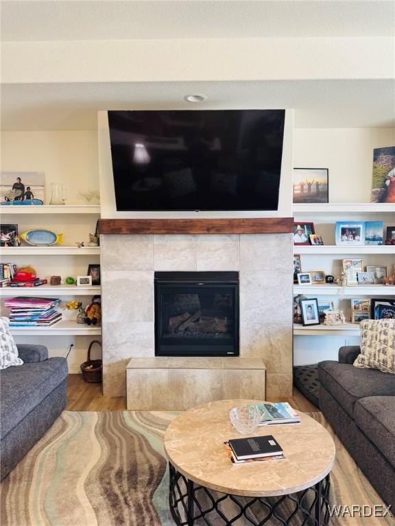 living area with a tiled fireplace and wood finished floors