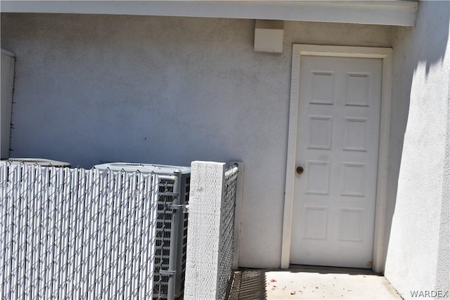 property entrance with central AC and stucco siding