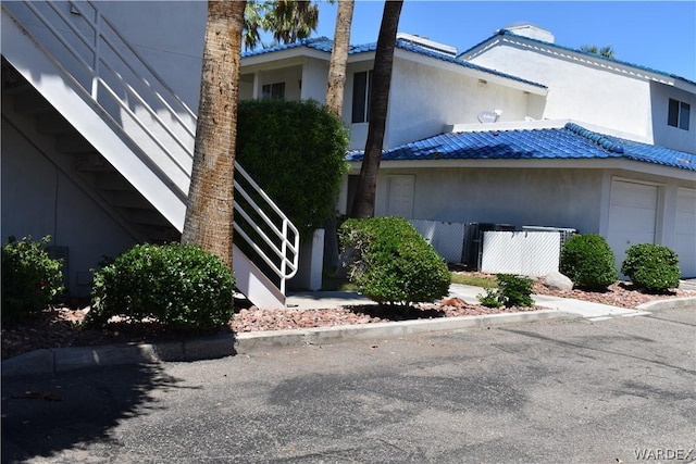 view of side of property with metal roof, stairway, fence, and stucco siding