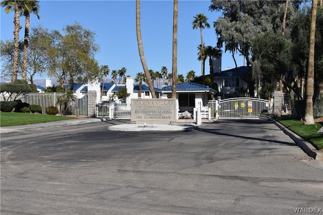 view of road featuring curbs, a gated entry, a residential view, and a gate