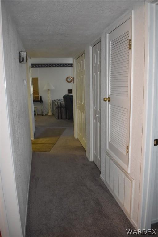 hallway featuring a textured ceiling and carpet flooring