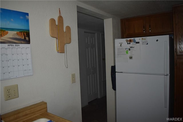 kitchen featuring mail area, brown cabinetry, and freestanding refrigerator