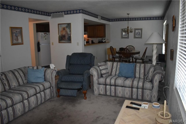 living room with carpet, visible vents, and an inviting chandelier