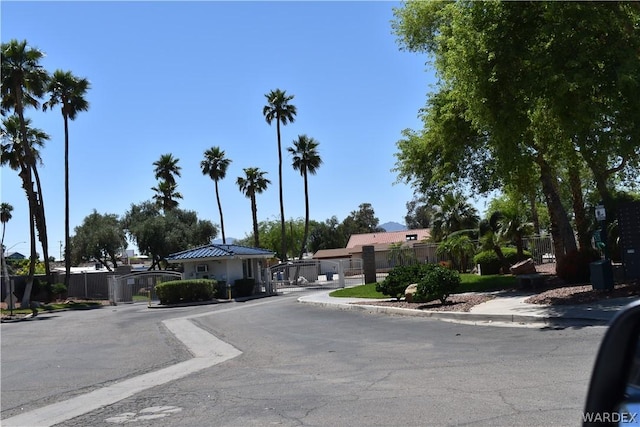 view of road featuring a gate, curbs, and sidewalks