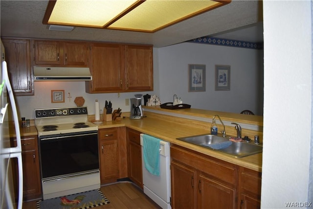 kitchen with light countertops, white appliances, a sink, and under cabinet range hood