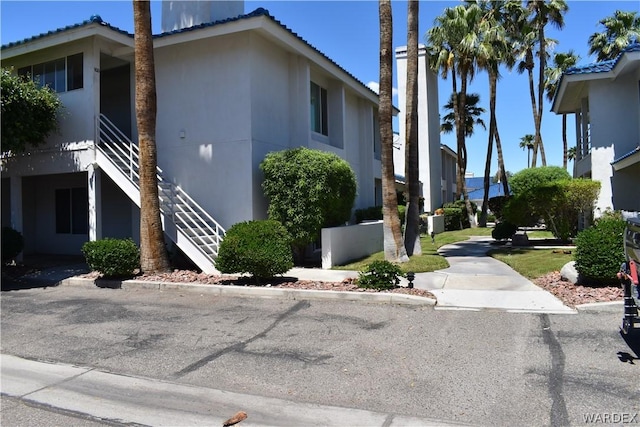 view of property exterior featuring stairway, a tile roof, and stucco siding