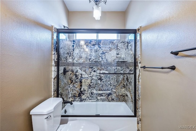 bathroom with toilet and shower / bath combination with glass door