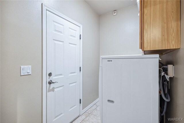 laundry room with cabinet space, baseboards, and light tile patterned flooring