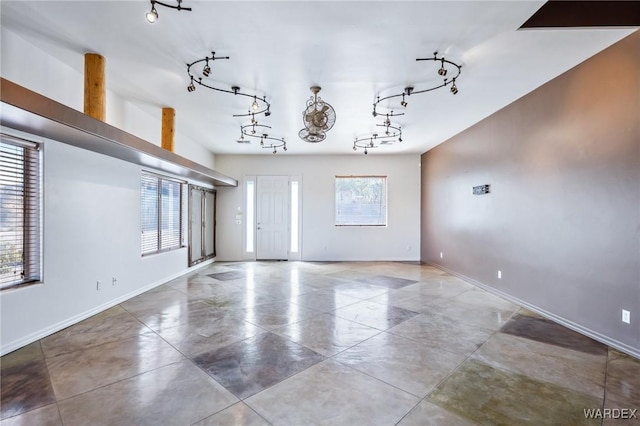 unfurnished living room featuring baseboards and track lighting