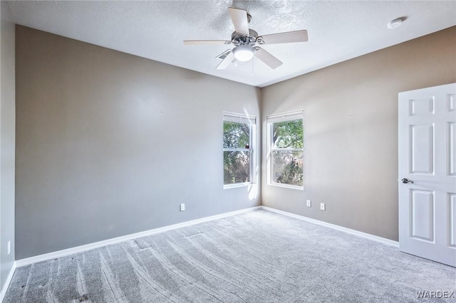 carpeted empty room with a textured ceiling, baseboards, and a ceiling fan
