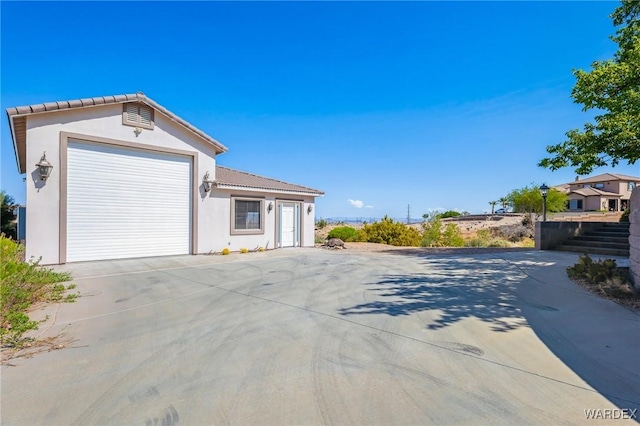view of home's exterior featuring concrete driveway, stucco siding, a tile roof, and a garage