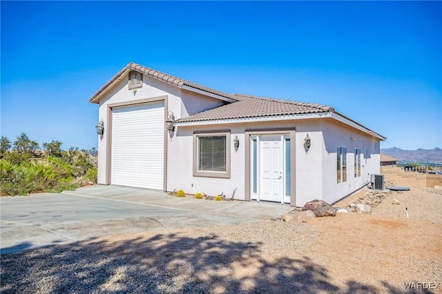 view of front of property with central air condition unit, a mountain view, stucco siding, and a tile roof
