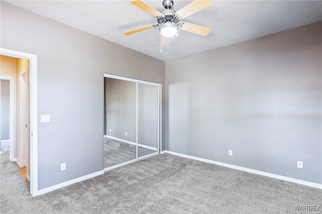 unfurnished bedroom featuring carpet, baseboards, a closet, and a ceiling fan