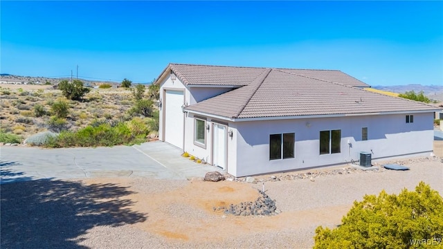 exterior space with a patio area, a tile roof, a garage, stucco siding, and central AC unit