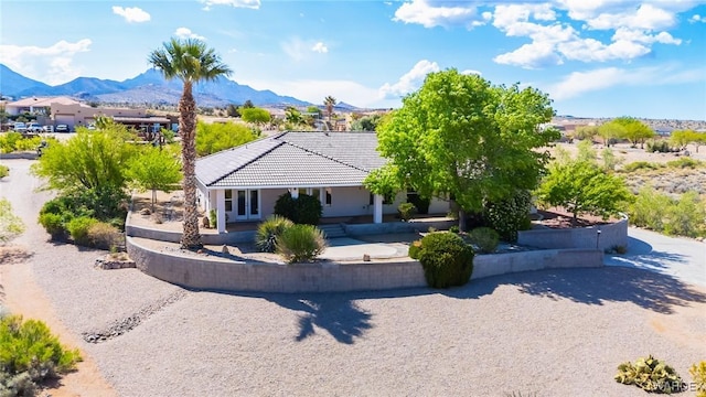 view of front facade with a mountain view, a patio, stucco siding, and a tiled roof