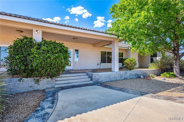 doorway to property featuring stucco siding and a tile roof