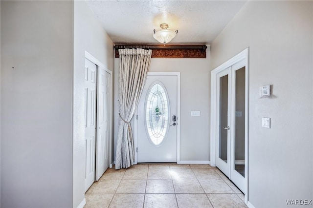foyer featuring baseboards, french doors, and light tile patterned floors