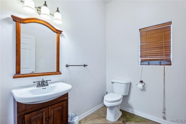 bathroom featuring toilet, baseboards, and vanity