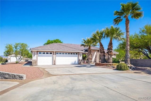 ranch-style home with stone siding, an attached garage, a tiled roof, stucco siding, and driveway