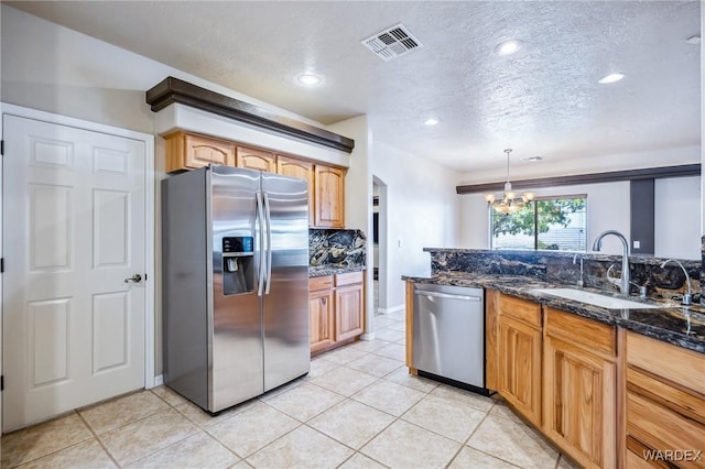 kitchen featuring visible vents, a sink, a chandelier, dark stone countertops, and stainless steel appliances