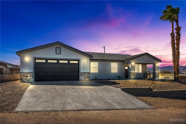 ranch-style house featuring stone siding, an attached garage, driveway, and stucco siding