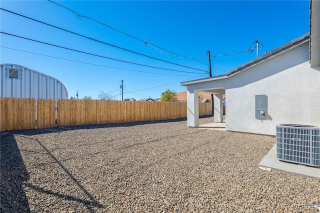 view of yard with fence, central AC unit, and a patio