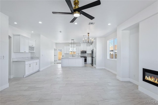 unfurnished living room with baseboards, a glass covered fireplace, visible vents, and recessed lighting