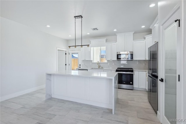 kitchen featuring a center island, light countertops, visible vents, backsplash, and appliances with stainless steel finishes