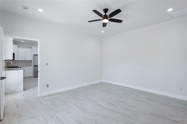 unfurnished room with recessed lighting, a sink, and baseboards