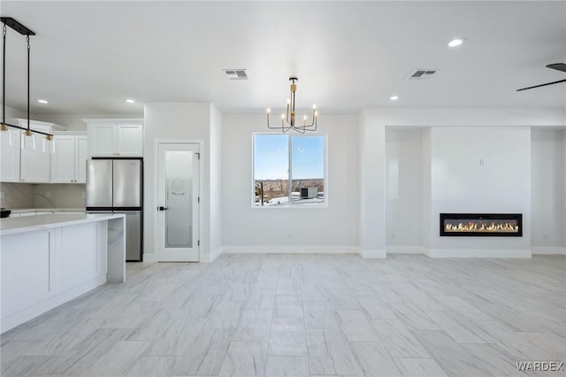 kitchen with visible vents, light countertops, freestanding refrigerator, and white cabinetry