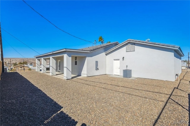 back of house with central AC and stucco siding