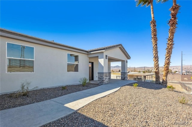 view of side of home featuring fence and stucco siding