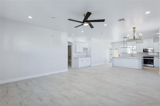 kitchen with visible vents, open floor plan, stainless steel appliances, light countertops, and ceiling fan with notable chandelier