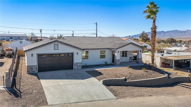 ranch-style house with a garage, driveway, stone siding, fence, and stucco siding