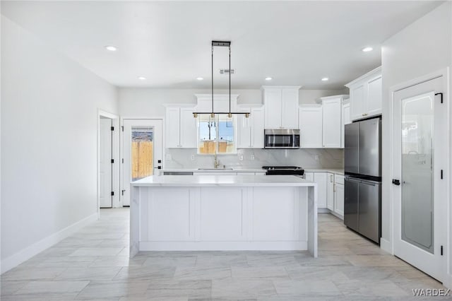 kitchen with a sink, a center island, light countertops, appliances with stainless steel finishes, and decorative backsplash