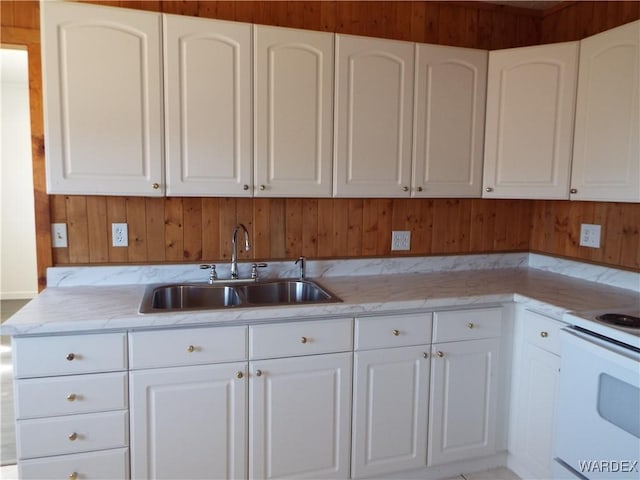 17516 N Ladera Dr, Dolan Springs, AZ 86441 - kitchen featuring wooden walls, light stone countertops, white cabinetry, and a sink