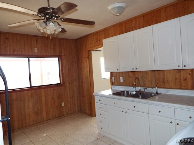 17516 N Ladera Dr, Dolan Springs, AZ 86441 - kitchen with a ceiling fan, a sink, white cabinetry, wood walls, and light tile patterned floors