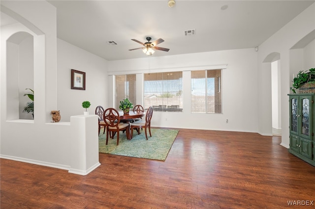 dining space with dark wood-style floors, arched walkways, and visible vents