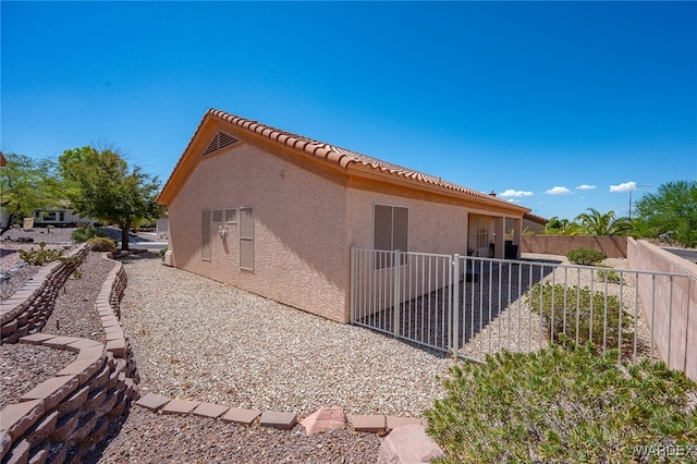 view of side of home featuring a tiled roof, a patio, fence, and stucco siding