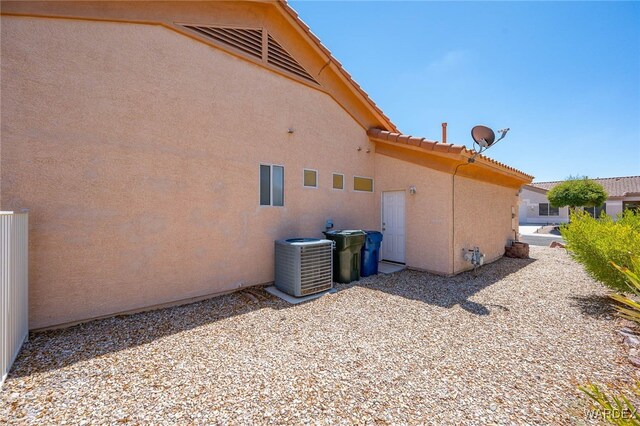 view of side of property with a tile roof, cooling unit, and stucco siding