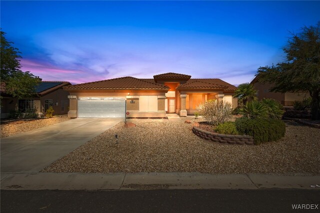 view of front of home with a garage, a tile roof, concrete driveway, and stucco siding