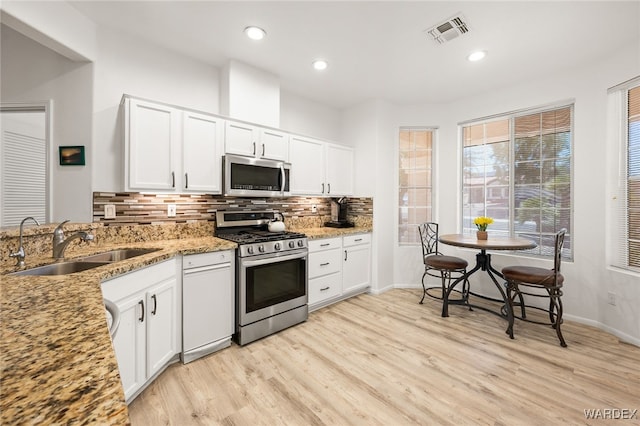 kitchen with a sink, visible vents, white cabinetry, appliances with stainless steel finishes, and light stone countertops