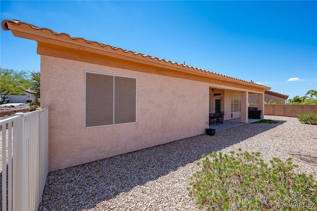 rear view of house with a patio, fence, and stucco siding