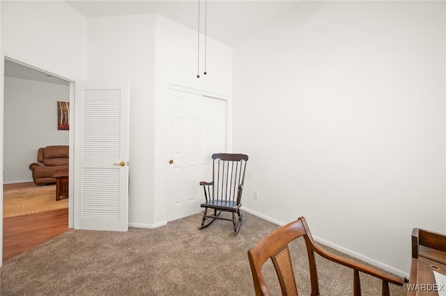 living area featuring carpet floors, a towering ceiling, and baseboards