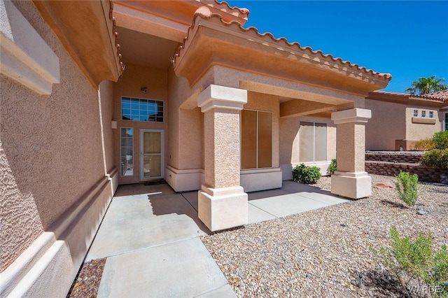 doorway to property featuring a patio, a tiled roof, and stucco siding