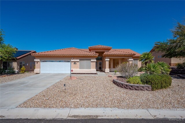 mediterranean / spanish home featuring an attached garage, a tiled roof, concrete driveway, and stucco siding