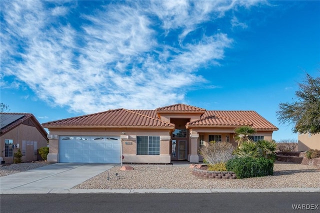 mediterranean / spanish-style home featuring concrete driveway, an attached garage, a tiled roof, and stucco siding