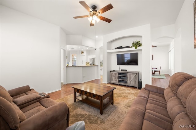 living area with baseboards, ceiling fan, built in features, and wood finished floors